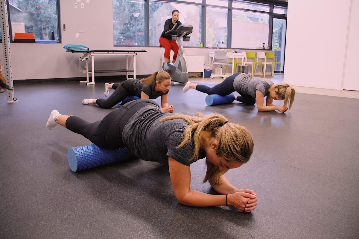A group class working through core exercises on the clinic's gym floor